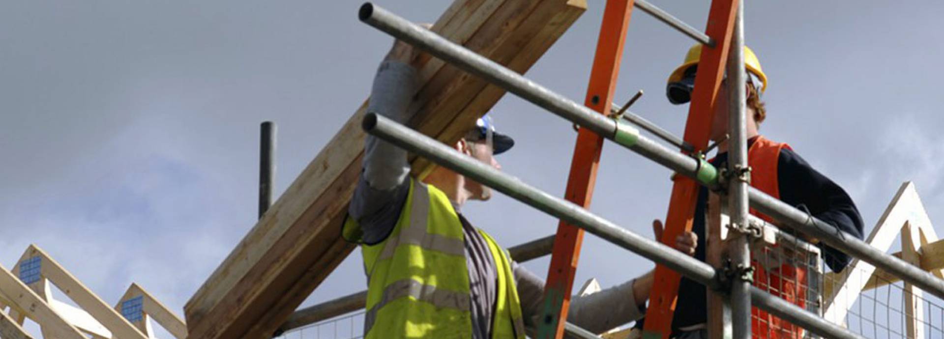 Bouwvakker met hout op ladder