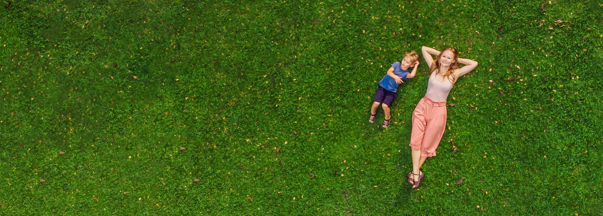 Een vrouw ligt met haar zoontje in het gras