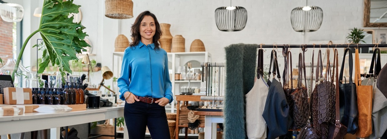Vrolijke jonge ondernemer in haar eigen trendy winkel