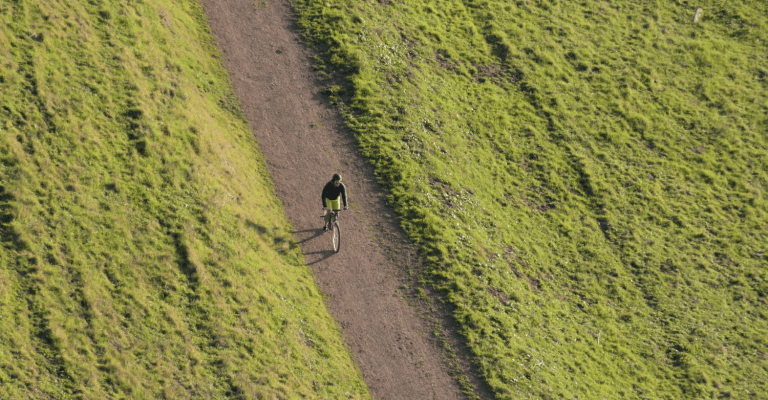 Een jongen op een fiets op een zandweg met links en rechts weiland