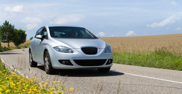 Grijze hybride auto rijd door mooi landschap