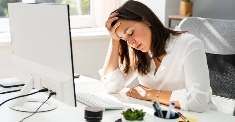 vrouw gestrest achter haar computer op het werk