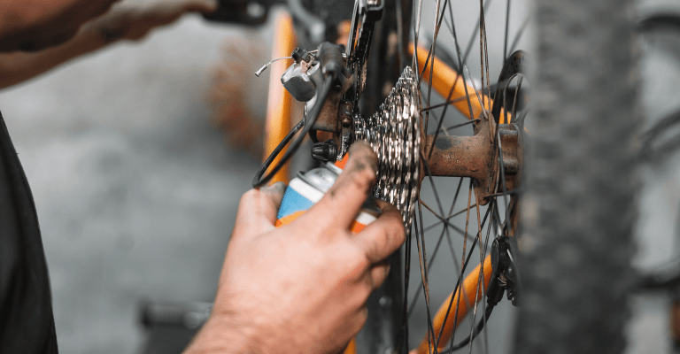 Fiets onderhoud, man sprayt olie op fietsketting
