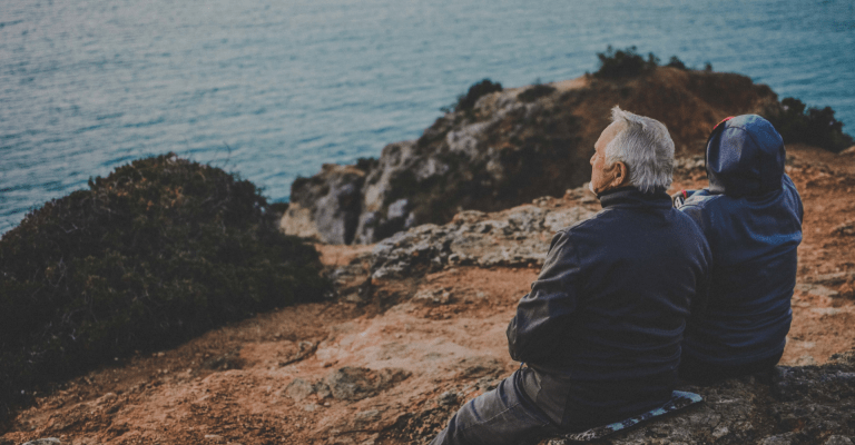 Een ouder stel zittend op een cliff bij de zee