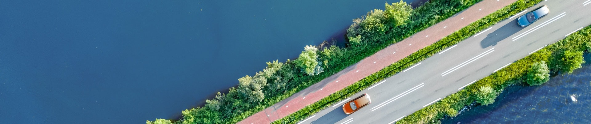 Auto's rijden op een weg met links en rechts daarvan water